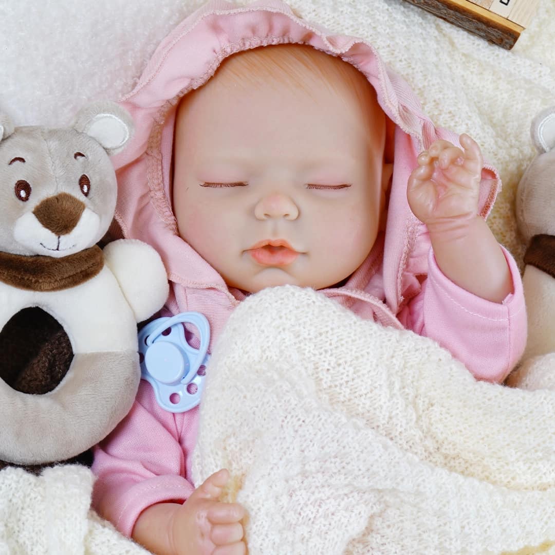 Sleeping lifelike doll dressed in snug pink outfit.