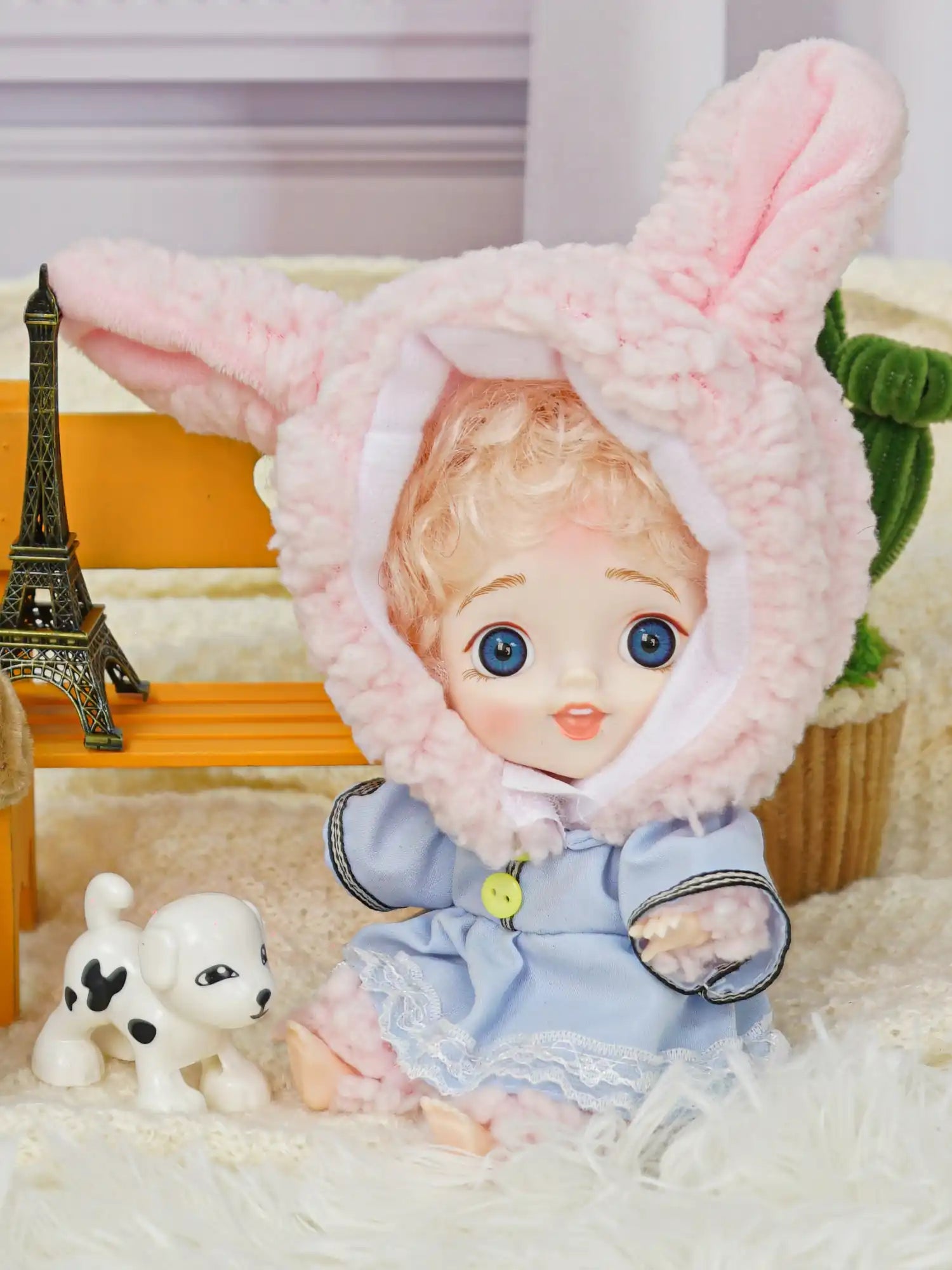 BJD with blue eyes in a rabbit costume alongside a white dog figurine.