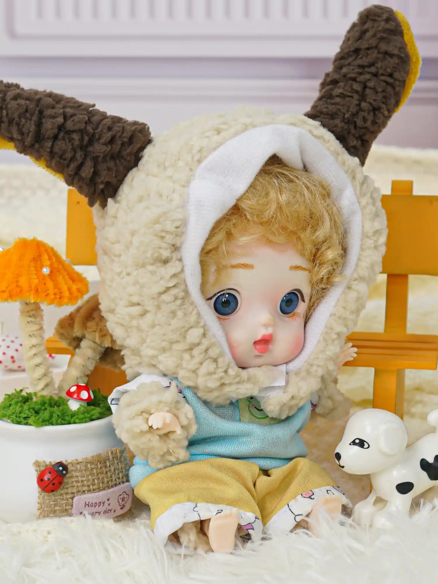 A golden-curled BJD wearing a lamb costume with adorable miniatures, including a Parisian Eiffel Tower replica.