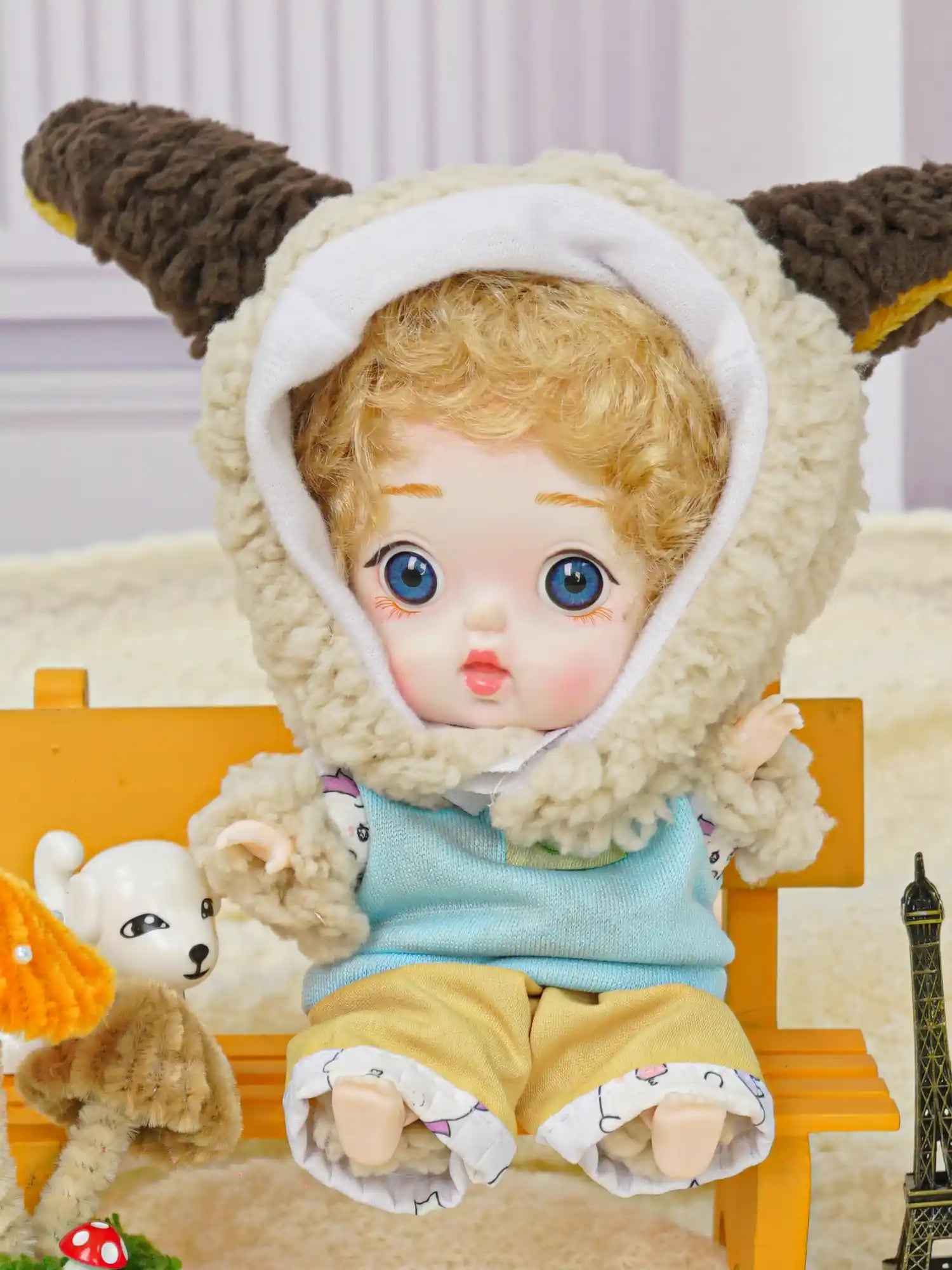 A ball-jointed doll with lamb ears and a loving gaze, nestled next to a small Eiffel Tower and a puppy figurine.
