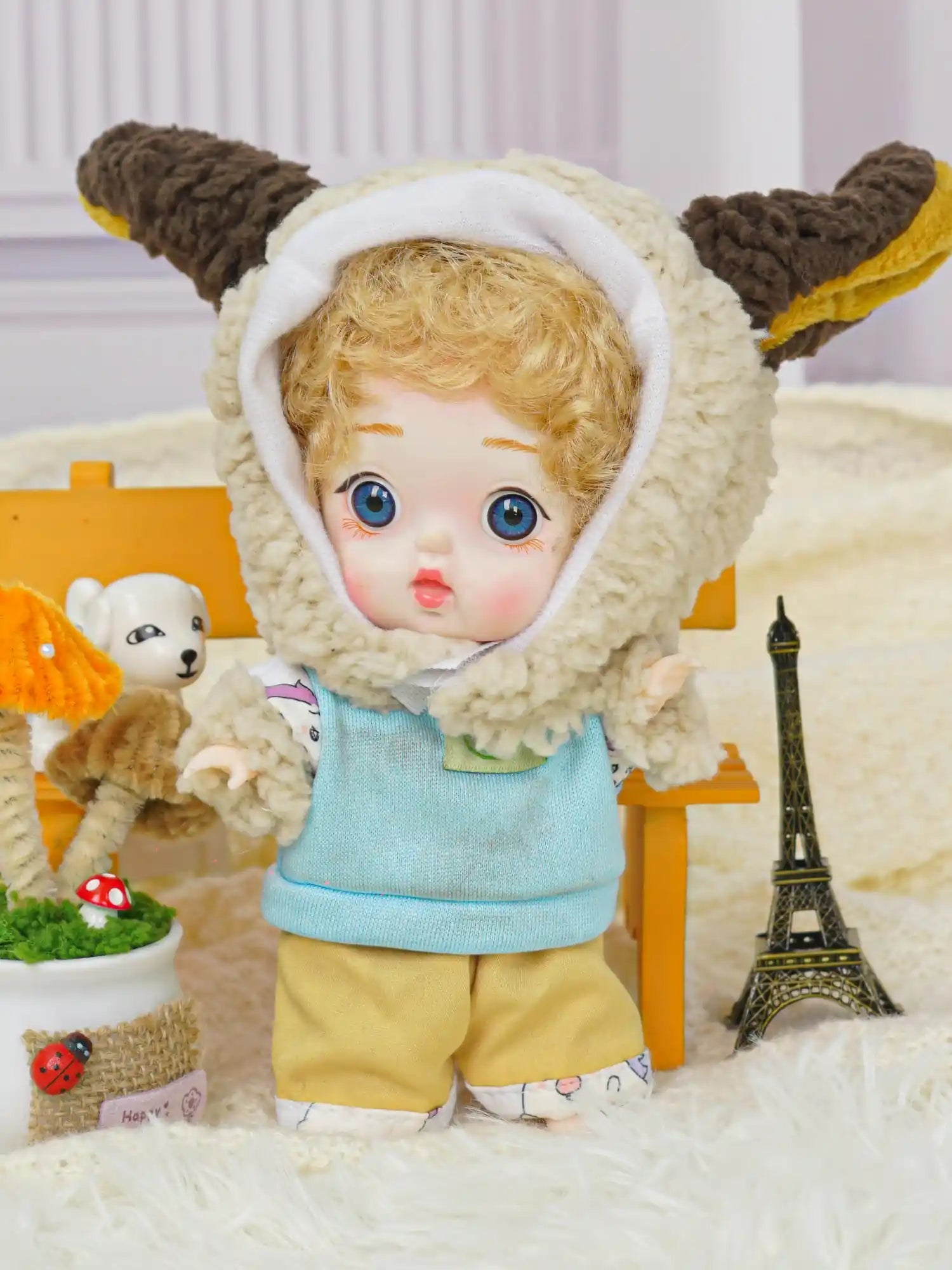 An expressive BJD dressed in a whimsical lamb hooded outfit, accompanied by playful miniature companions.
