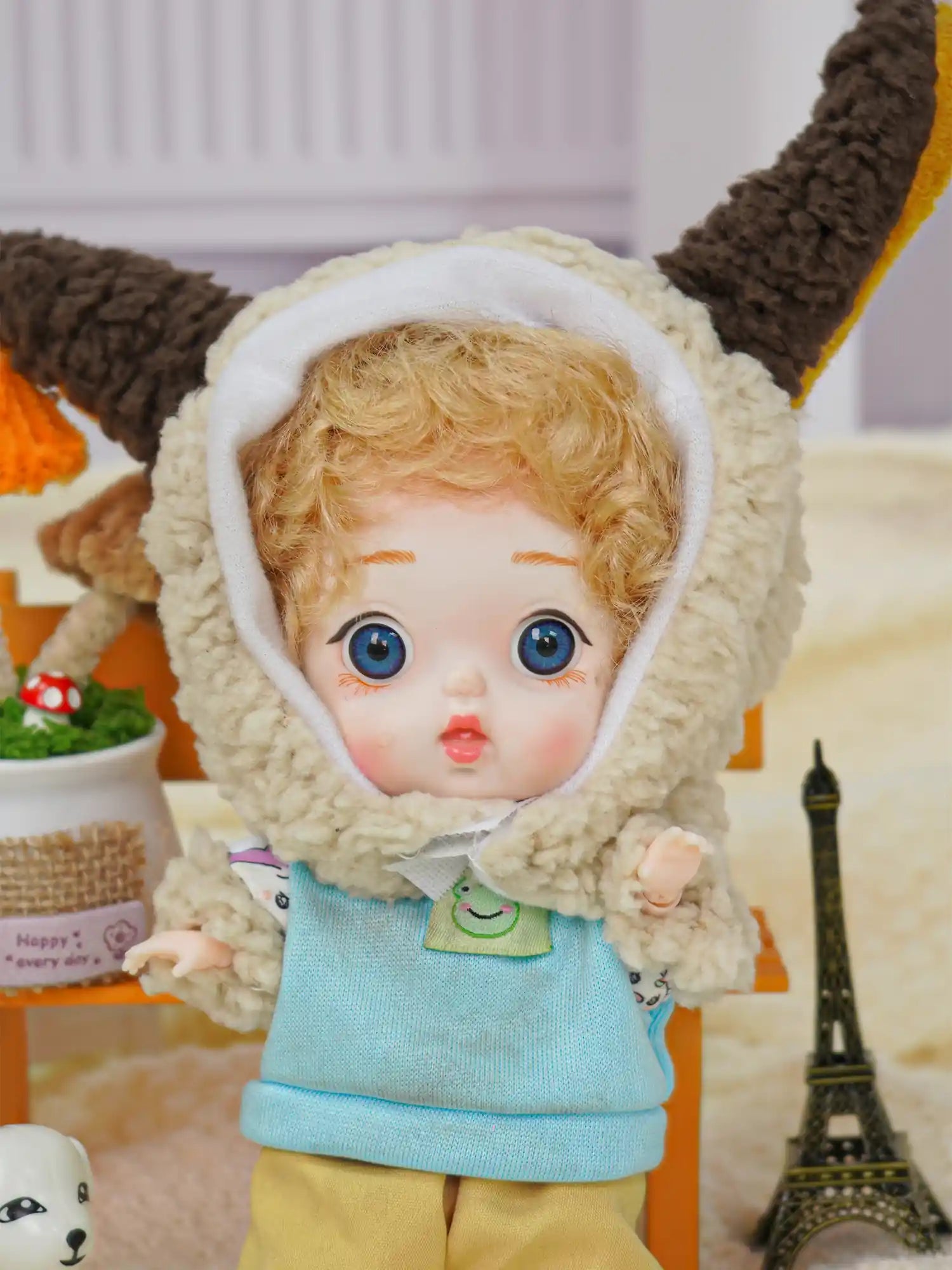 A BJD in a cute lamb outfit holds the attention with its vivid eyes, with a mini Eiffel Tower and toy dog as accents.