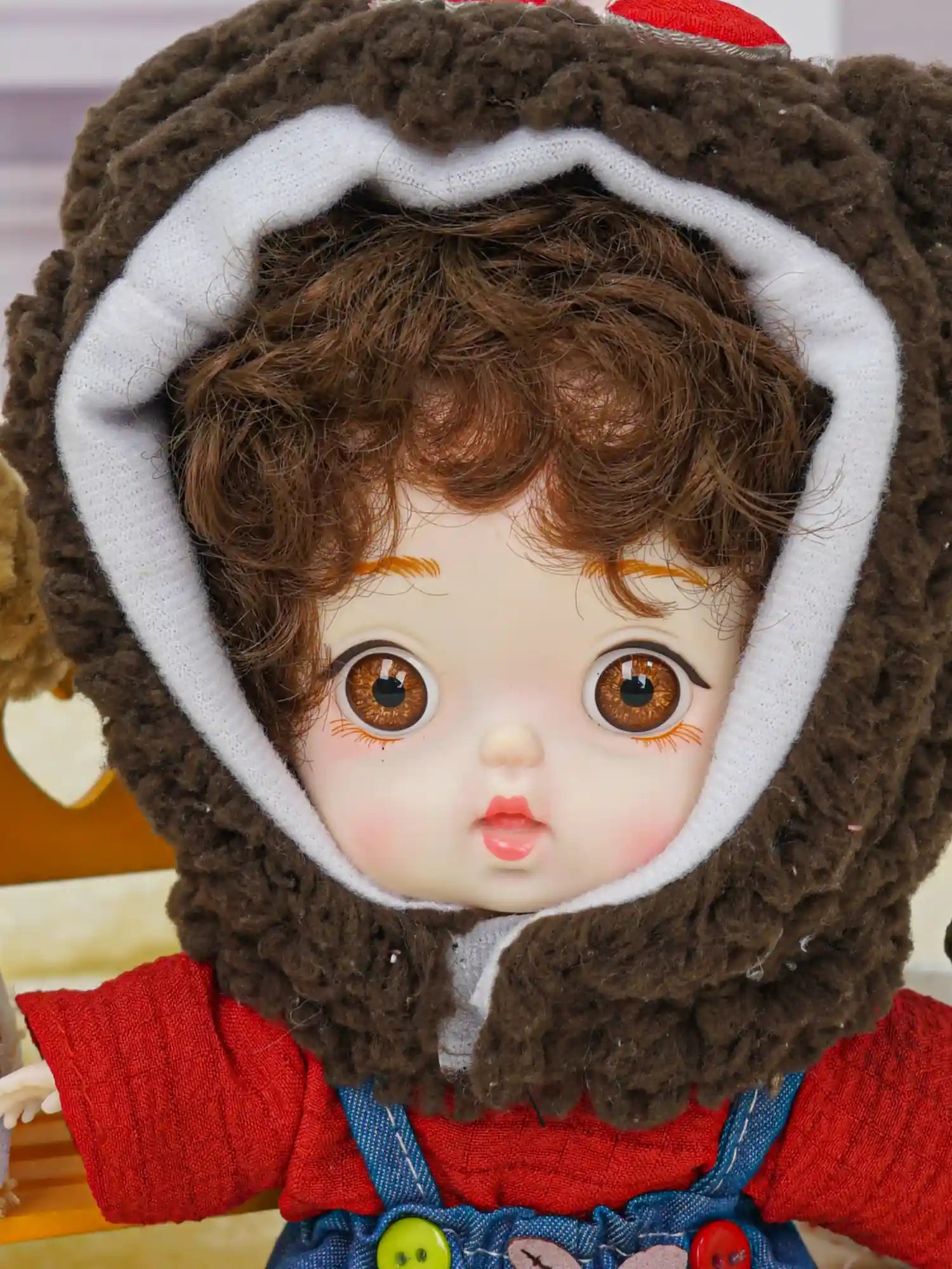 A brown-haired doll in a soft bear hood, with a petite Eiffel Tower model and a porcelain puppy by its side.