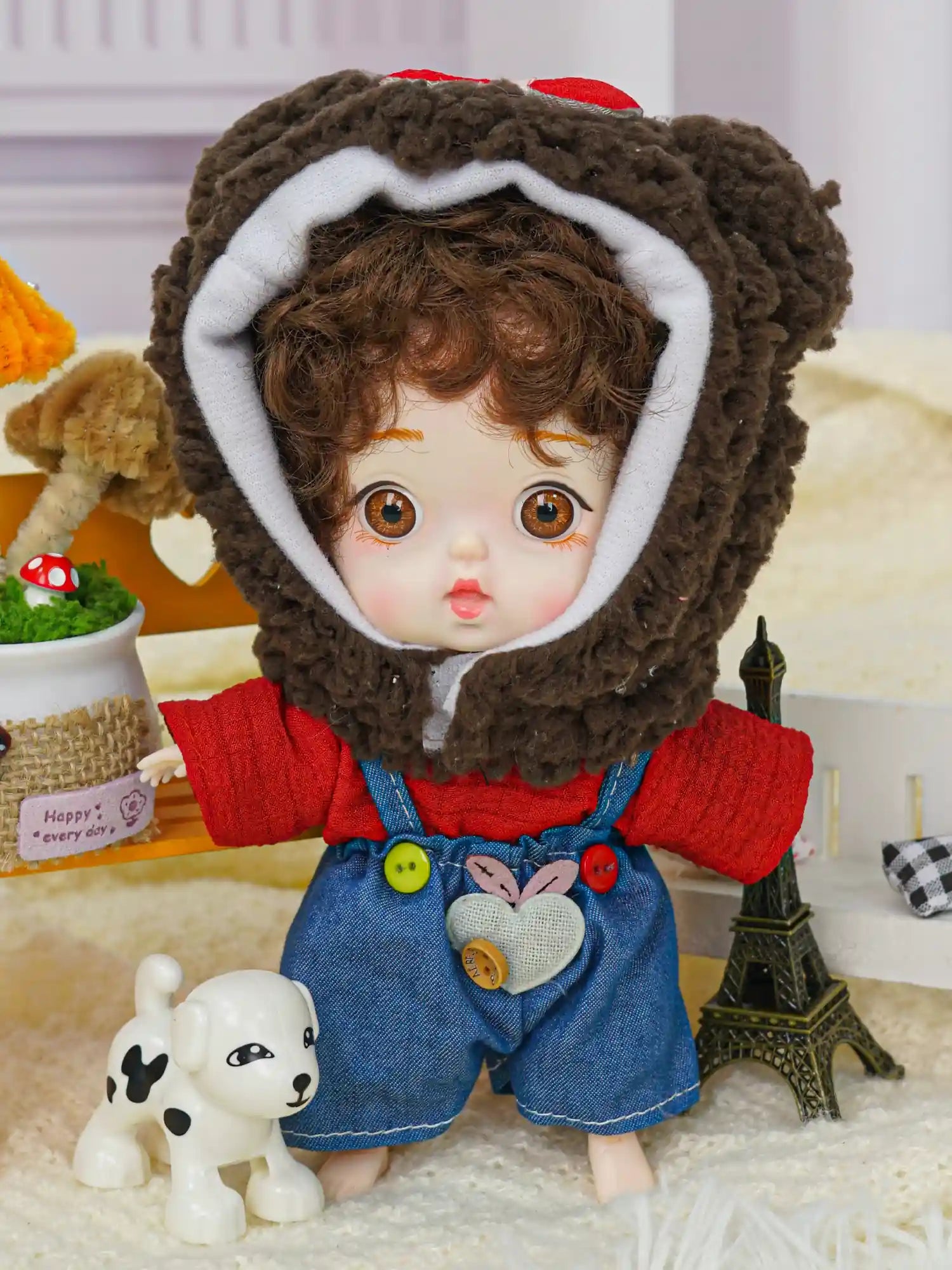 A playful doll in a brown bear cap, with a small Eiffel Tower and a toy dog adding charm to the scene.