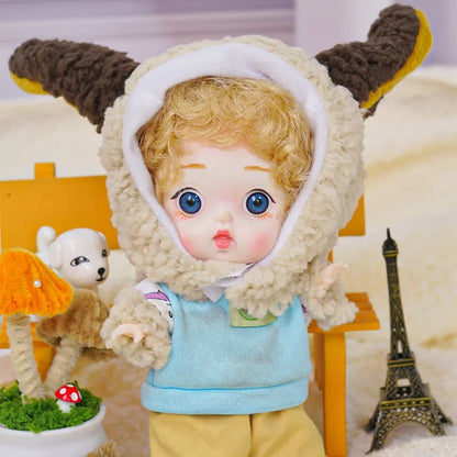 A BJD with bright blue eyes and lamb ears hood stands amidst a scene with a toy dog and a miniature Eiffel Tower.