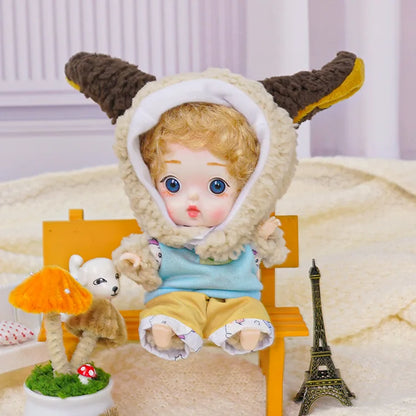 A golden-curled BJD wearing a lamb costume with adorable miniatures, including a Parisian Eiffel Tower replica.