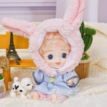 BJD with golden curls in a bunny outfit, next to a miniature Parisian landmark.