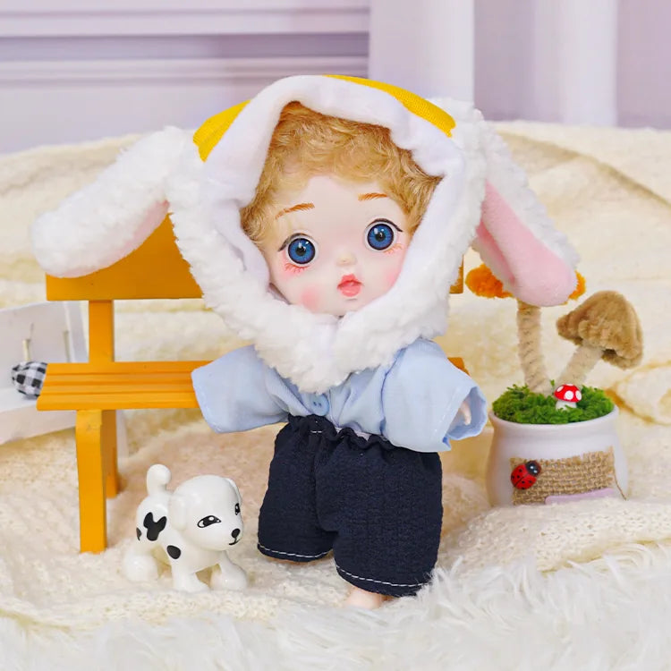 A ball-jointed doll in a fleece lamb cap, sharing a soft rug with a toy dog and tiny enchanting accessories.
