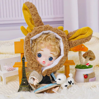 A blue-eyed doll with rabbit ears, posed with a small Eiffel Tower model and a toy canine on a plush background.