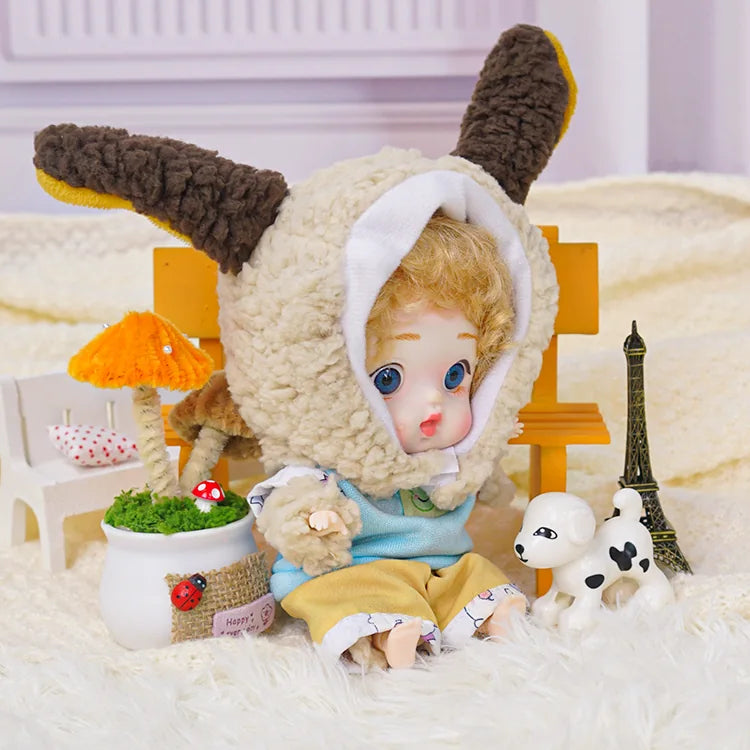 The BJD's captivating blue eyes shine from beneath a lamb's hood, with a miniature world around it.