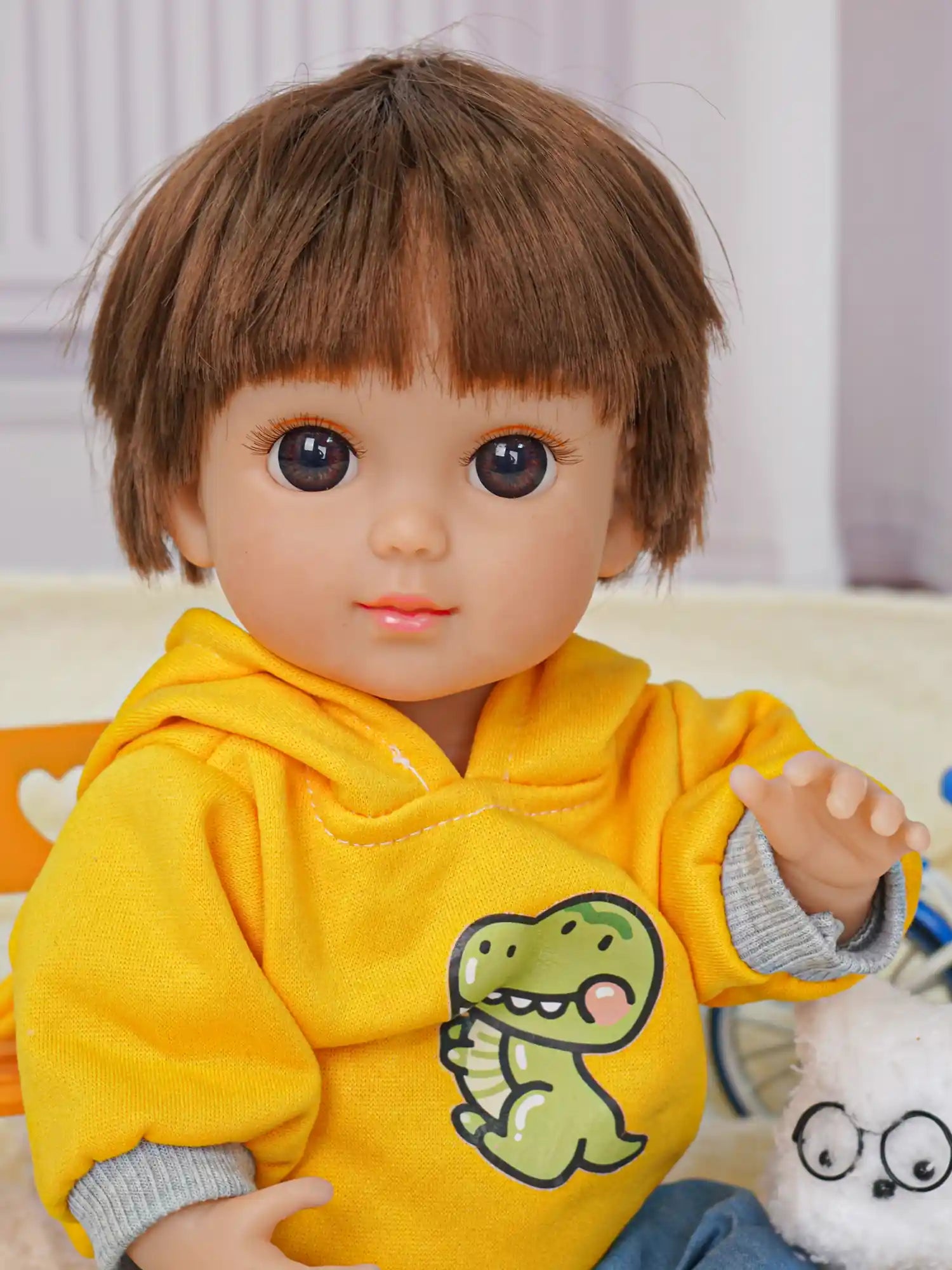 Toy doll in bright yellow and blue, with a plush canine companion and a miniature bicycle.