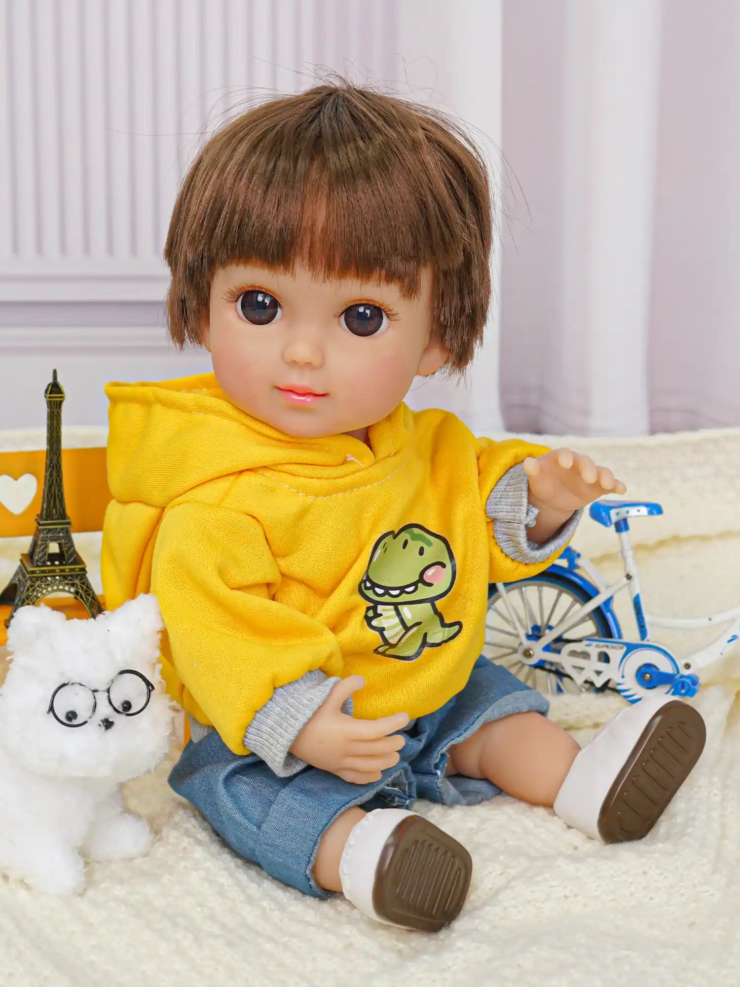 Doll in a vibrant outfit, sitting on a rug with a toy dog and a miniature bicycle nearby.