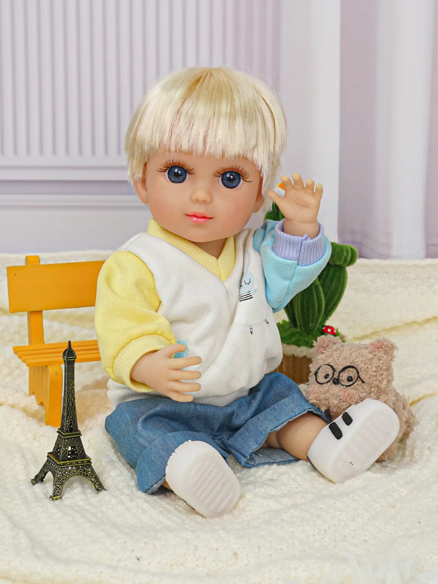 Playful doll with a friendly expression, dressed in a yellow top and blue pants, sitting on a rug.