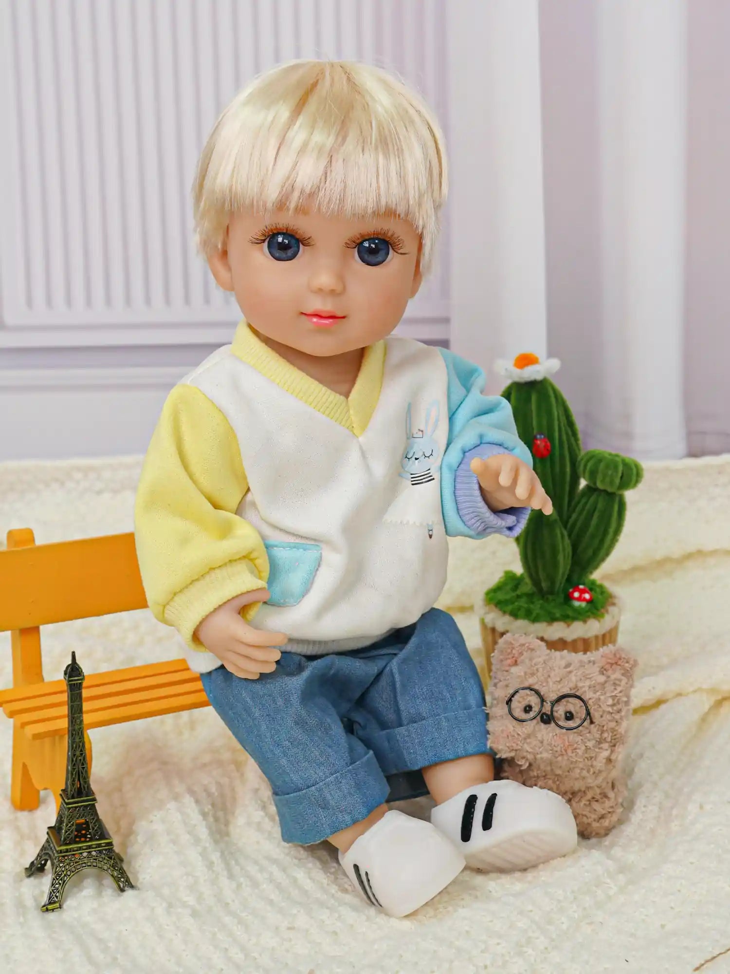 Cute toy doll with blonde bangs, in a colorful outfit, accompanied by a toy owl and Eiffel Tower.