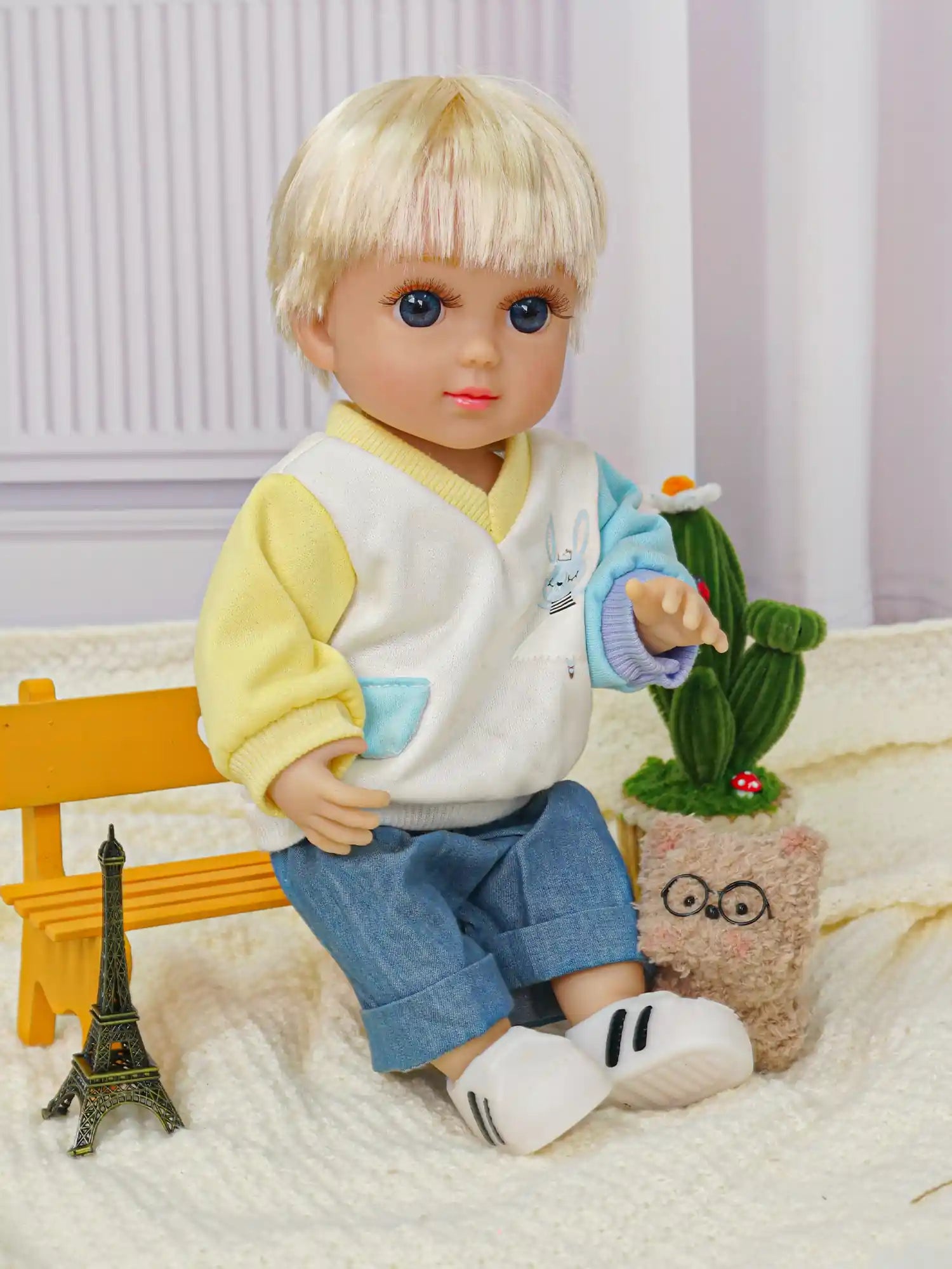 Adorable doll with striking blue eyes, sporting a casual modern look, with a knit toy companion.