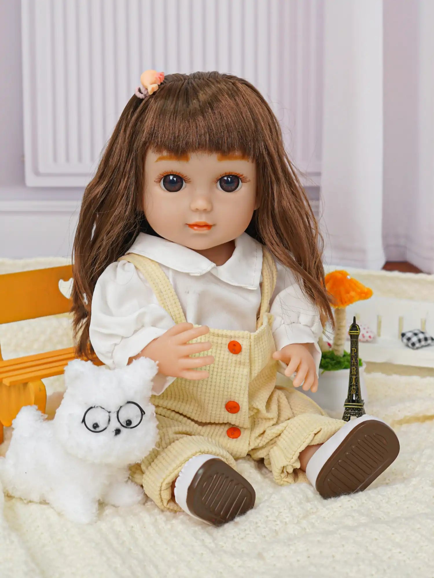 Childlike doll in white and yellow, with a toy dog and miniature Eiffel Tower.