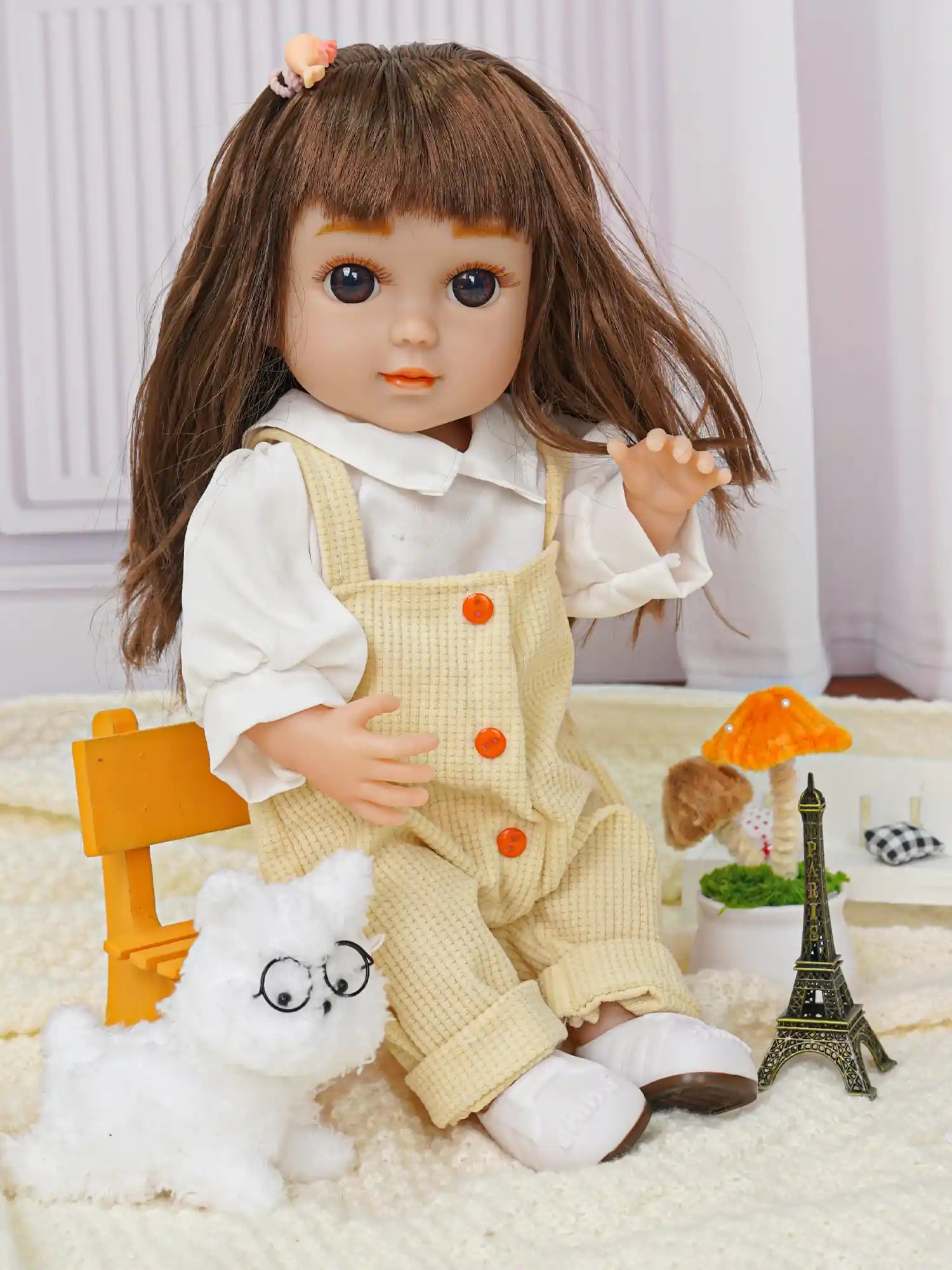 Doll with brown hair, yellow overalls, plush dog, and Eiffel Tower model.