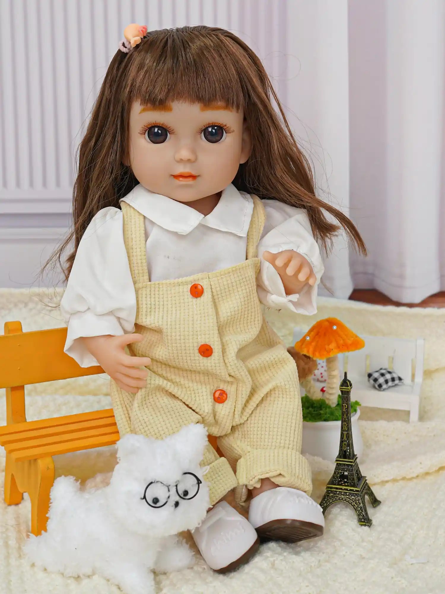Brown-haired doll, white blouse, yellow overalls, with a stuffed dog and Eiffel Tower.