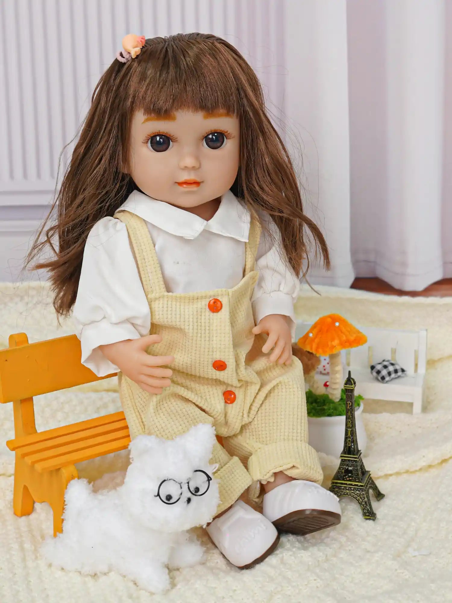 Doll with toy dog wearing glasses and a tiny Eiffel Tower nearby.