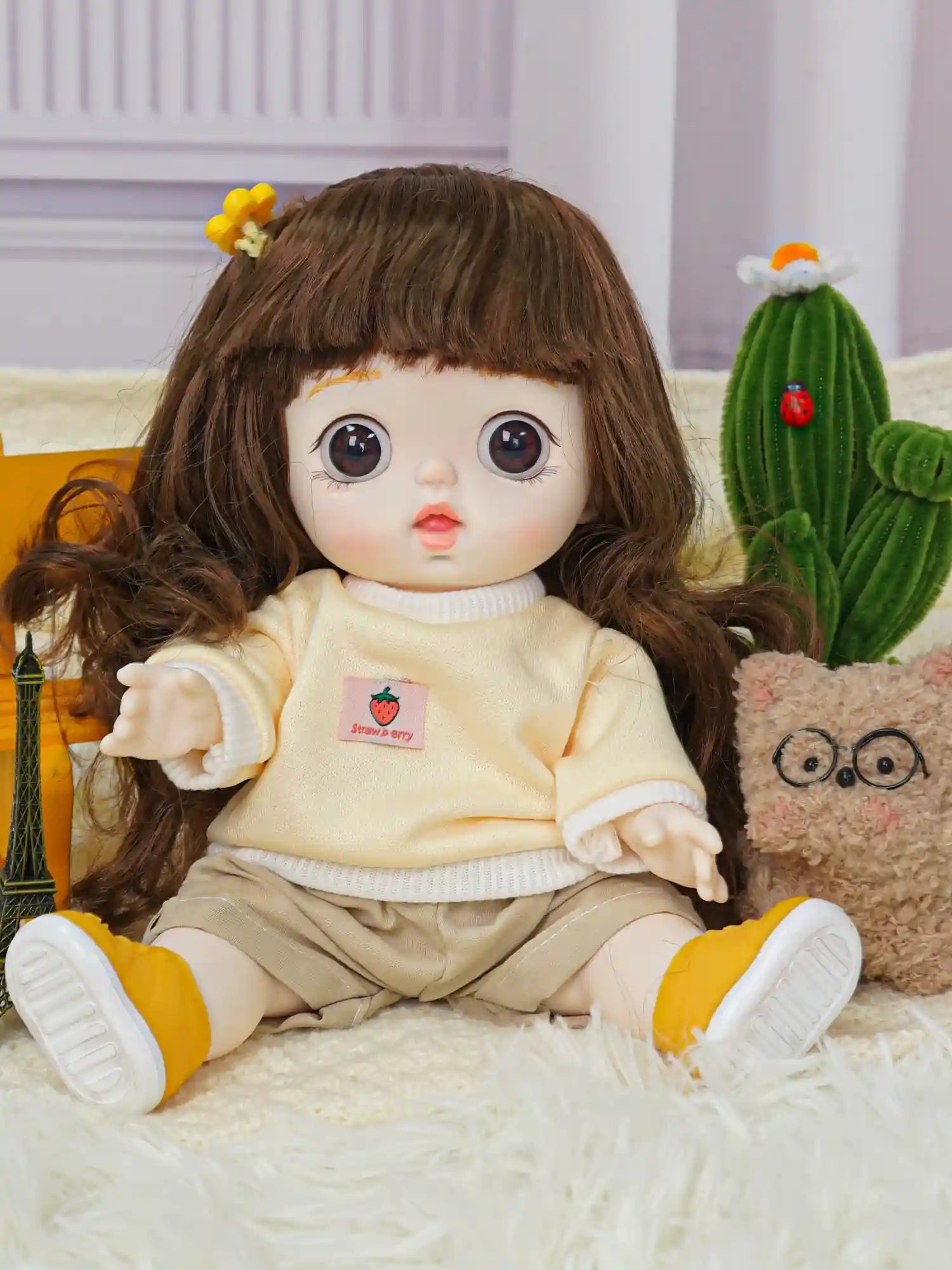 Doll with a soft, pastel-themed outfit and an animated expression, alongside a cute, bespectacled plush toy.