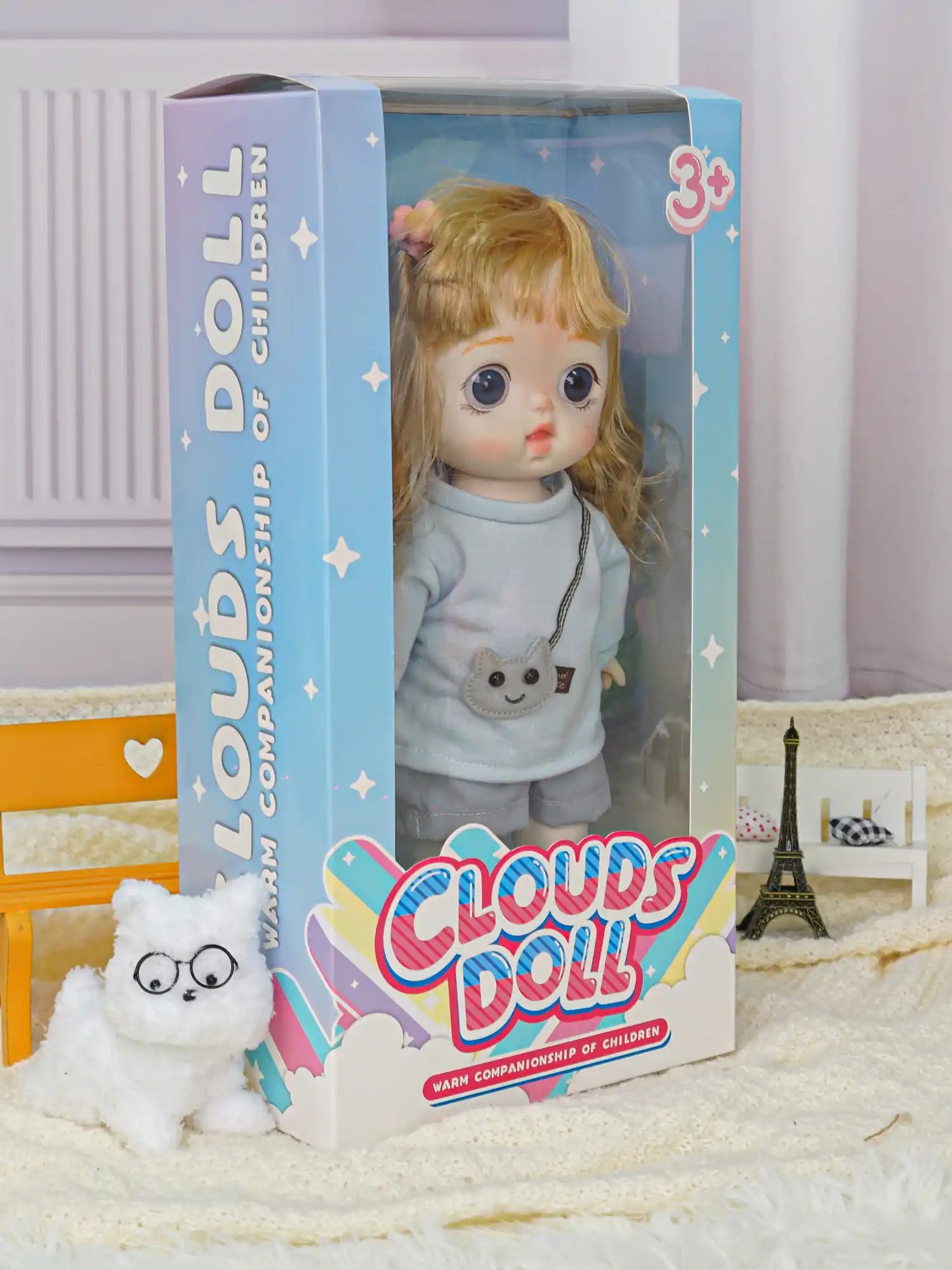 A miniature doll with a friendly expression, dressed in a blue outfit and shorts, in a room with a plush toy and miniature landmarks.