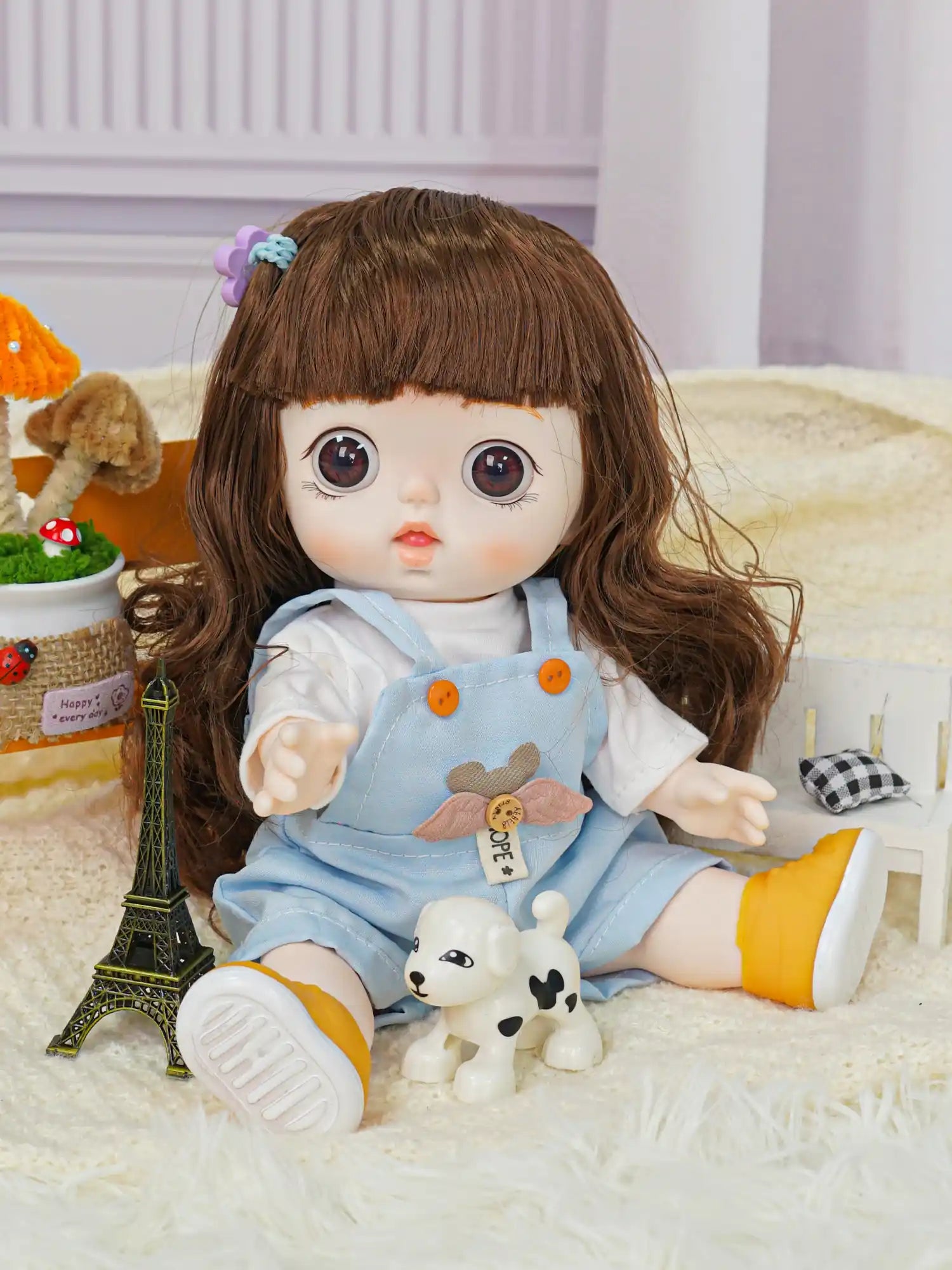 A doll with a curious expression and wavy hair, clad in a blue onesie, shares the frame with a model of the Eiffel Tower.