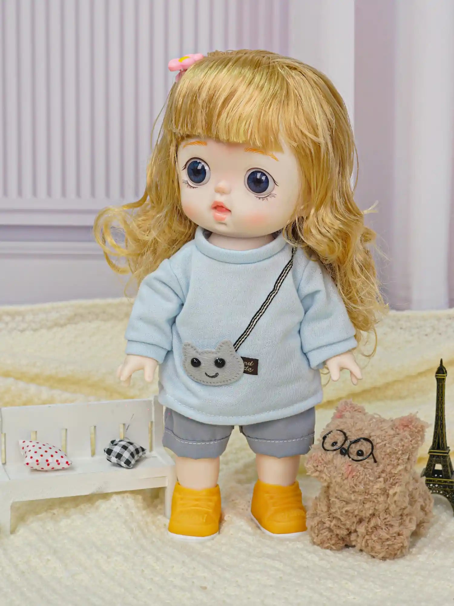 Kid's doll with a lifelike gaze and casual chic style, sharing a space with a furry friend and checkered cushions.