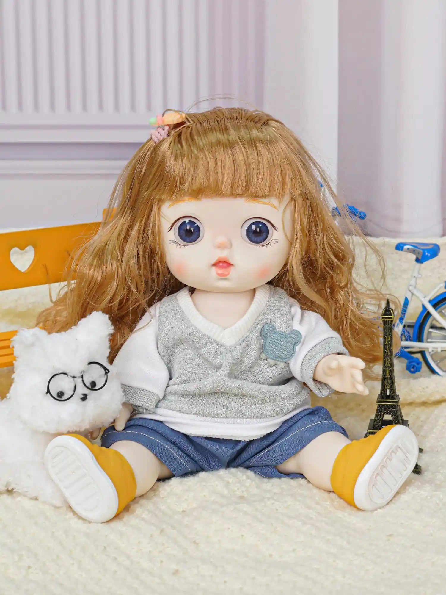 A toy doll with expressive features paired with a white fluffy dog wearing round spectacles, in a playroom setting.