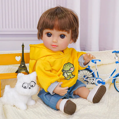 Childlike doll sitting with a yellow top, blue shorts, white dog toy, and a small bike.