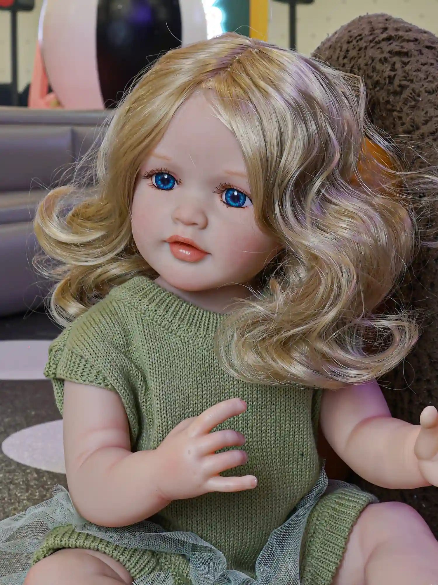 Marvel at the delicate artistry of our reborn doll, her sapphire eyes a striking contrast to the subtle green of her attire, capturing the essence of childhood innocence.