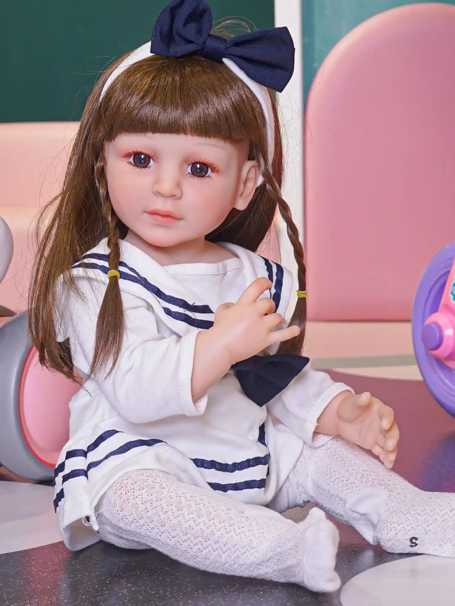 Detailed play doll featuring human-like eyes and expression, dressed in a purple top and patterned skirt, resting on the floor.
