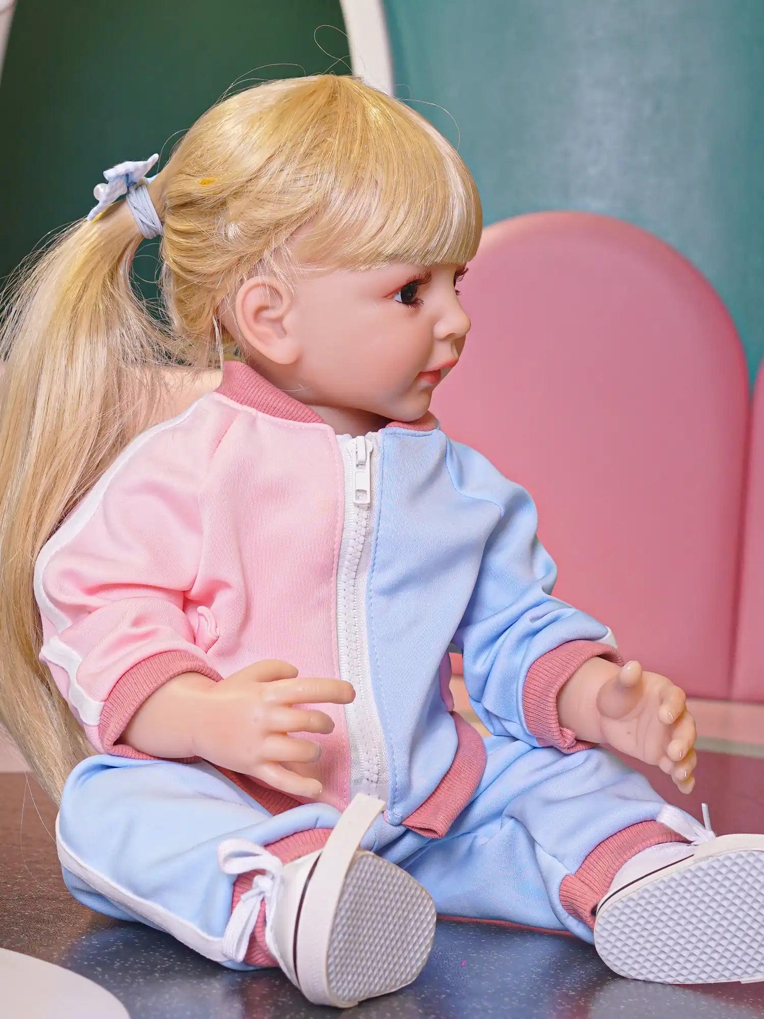 Doll with blonde bob and pastel tracksuit, seated on the floor.