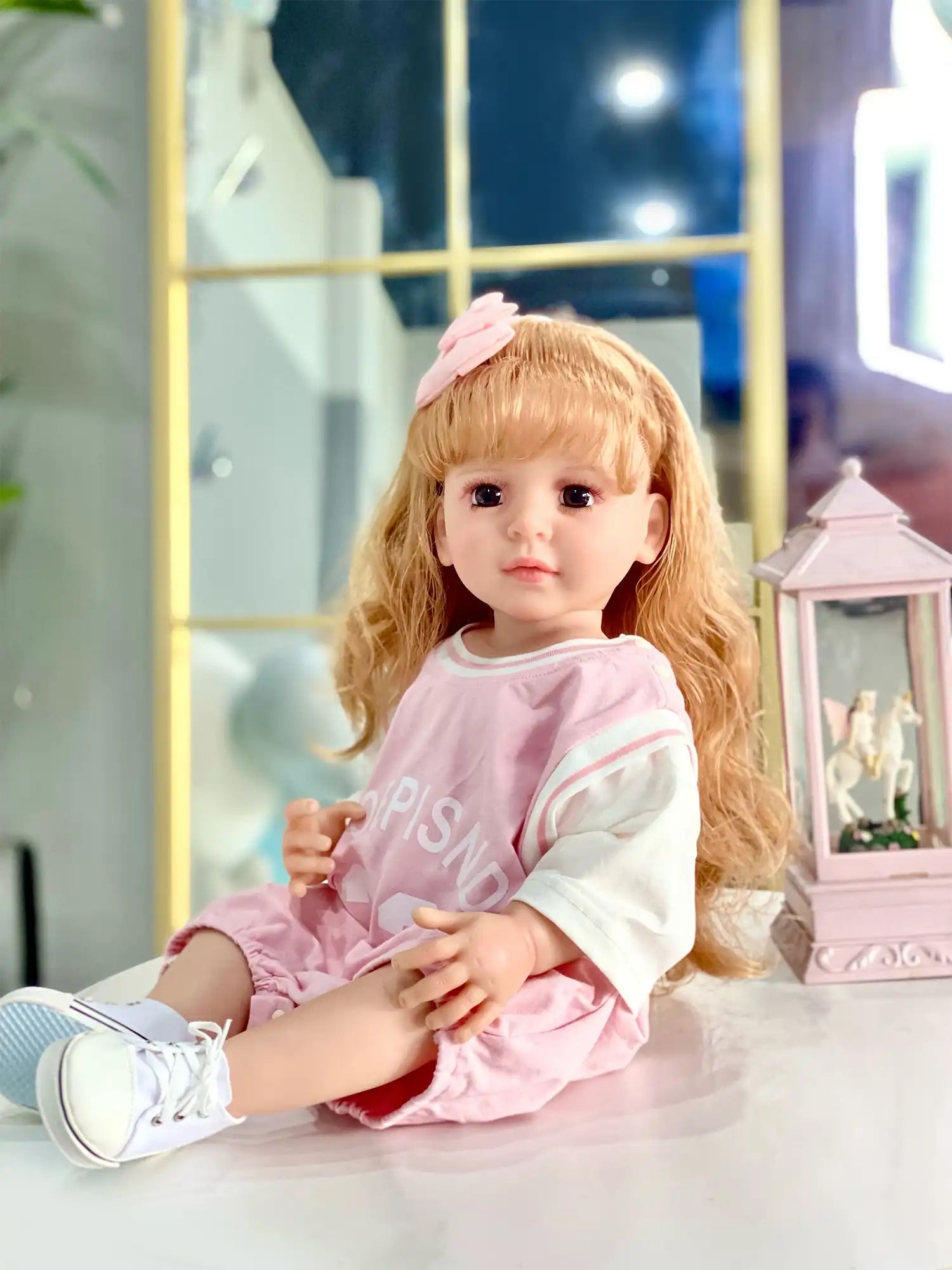 Toddler doll with a thoughtful gaze, adorned with a soft pink bow, dressed in a sporty outfit, celebrating a cozy holiday season.