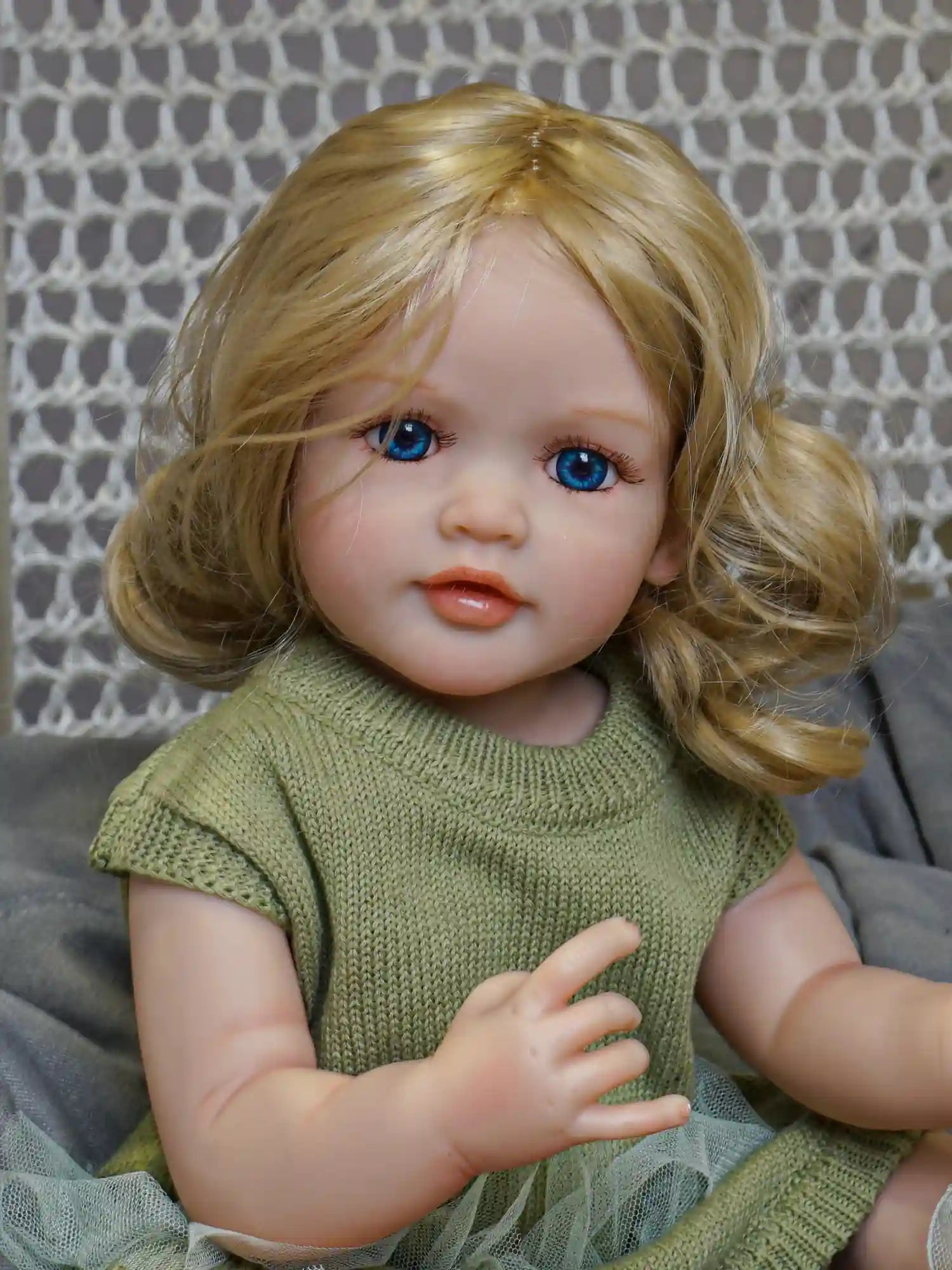 Our exquisite reborn doll with her realistic features and sun-kissed hair, clothed in an earthy green dress, is a portrait of doll perfection.