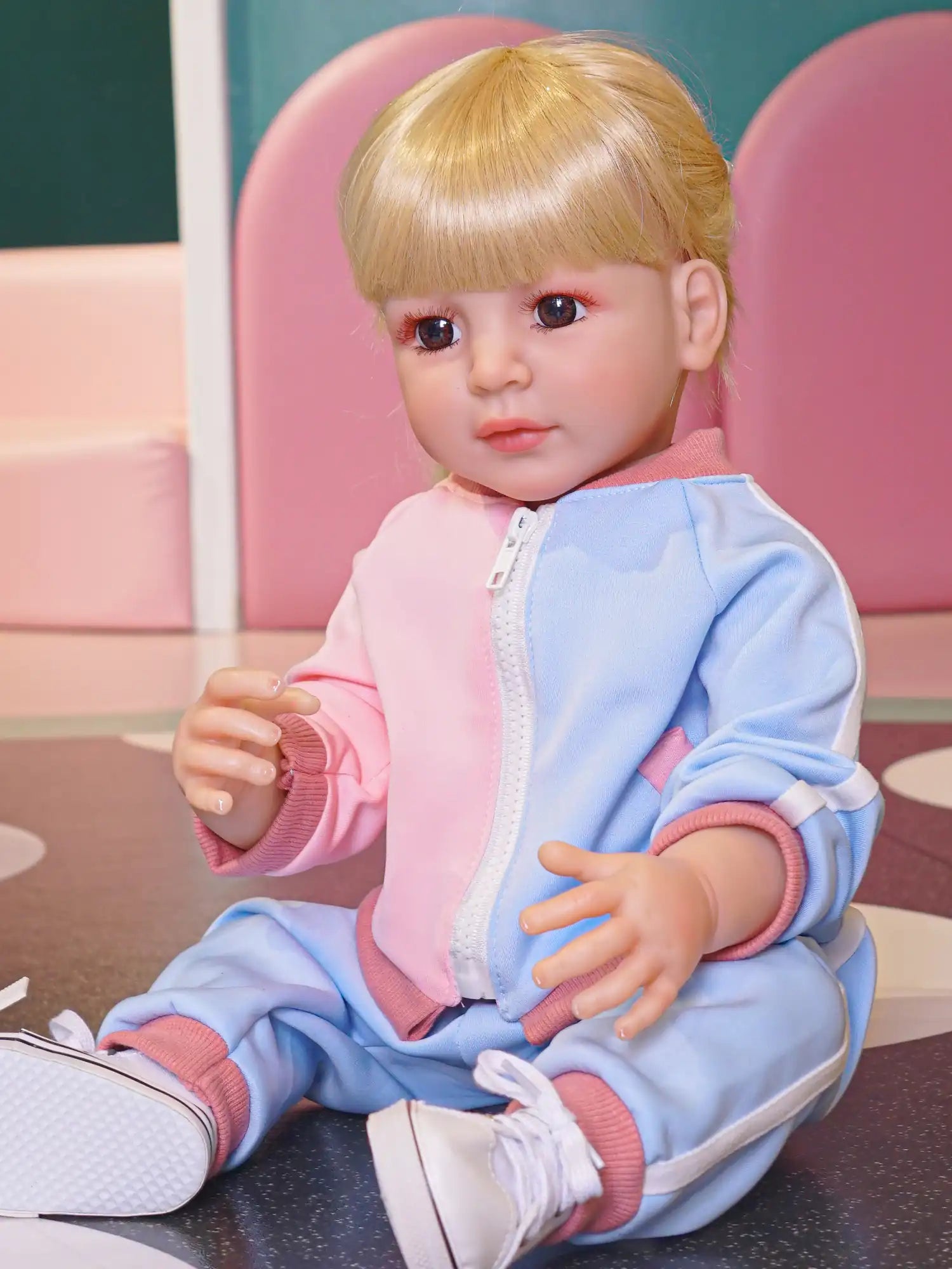 Toddler doll with golden hair, dressed in a comfy two-tone tracksuit.