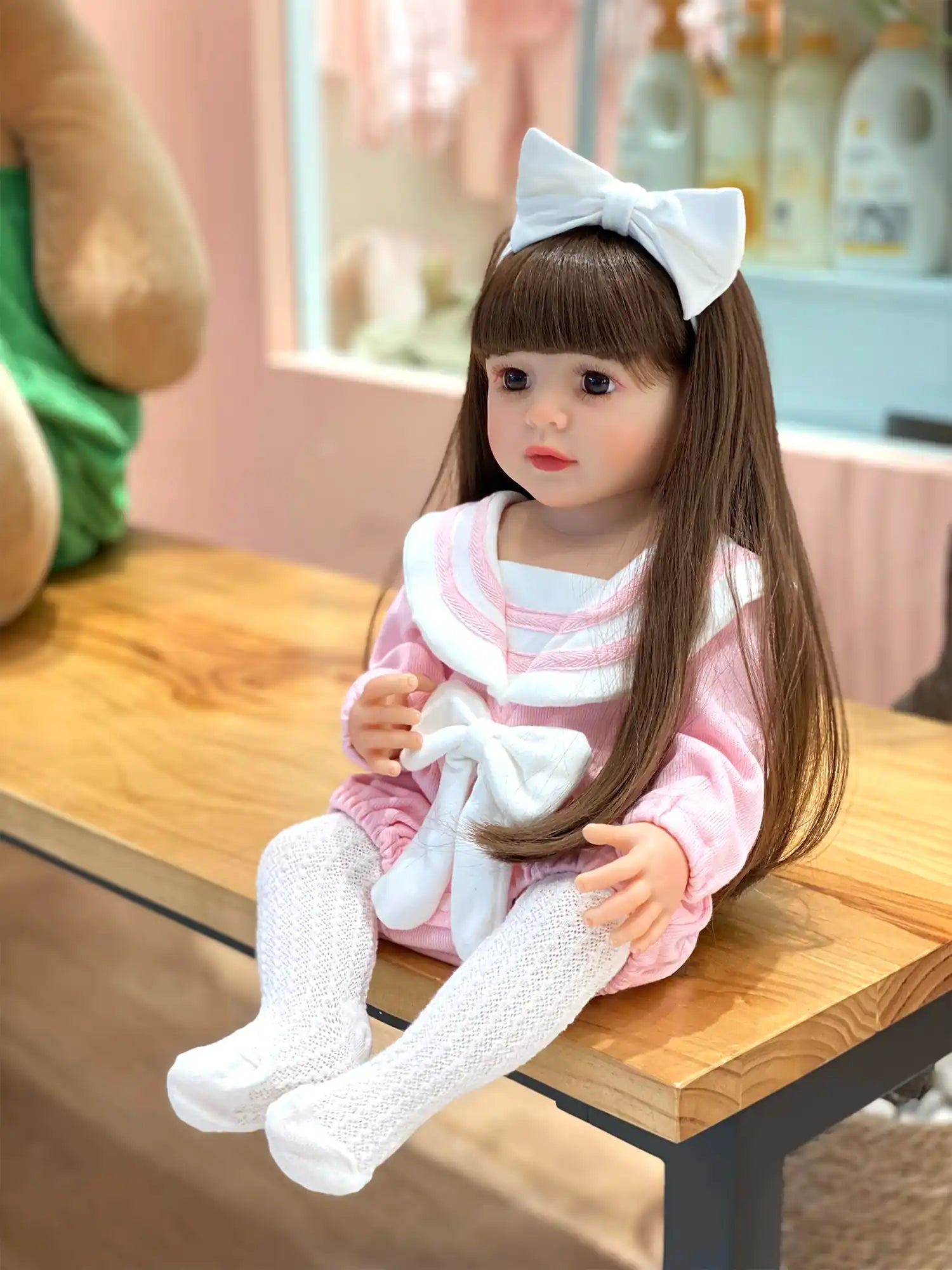 Doll in pink with white accents, posing in front of a candy-themed backdrop.