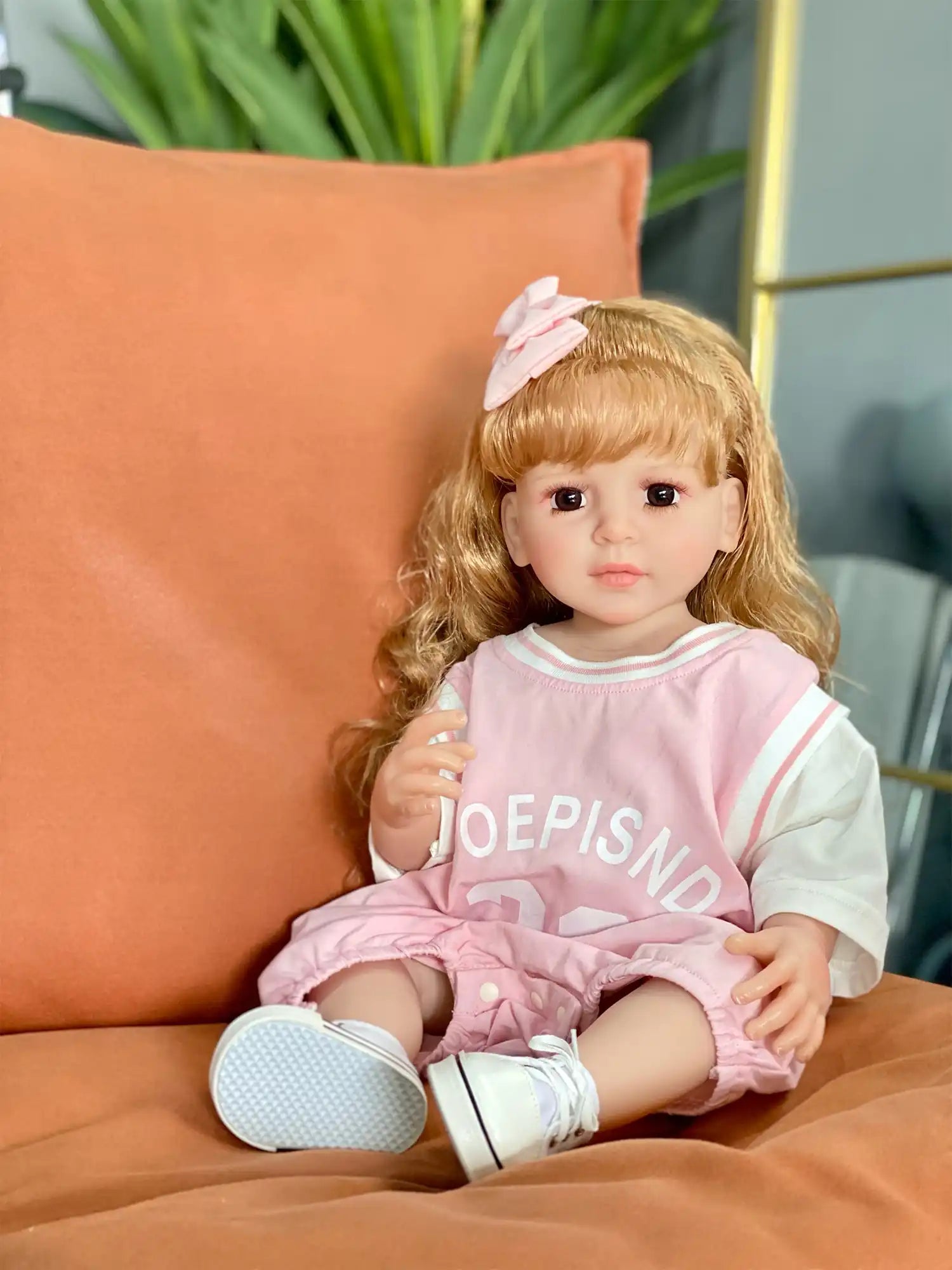 Realistic doll capturing a moment of childlike innocence, wearing a pink and white ensemble, against a holiday backdrop.