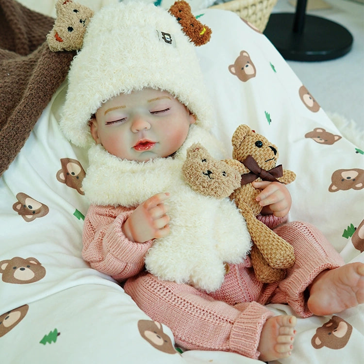 Reborn baby doll tightly holding two stuffed bears, wearing a cute white sheep hat, with eyes gently closed.