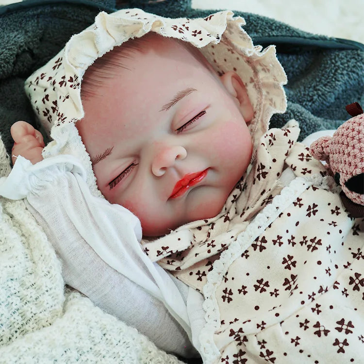 The reborn baby doll lying comfortably, dressed in a floral outfit with a bonnet, with a serene expression while holding a soft teddy bear.