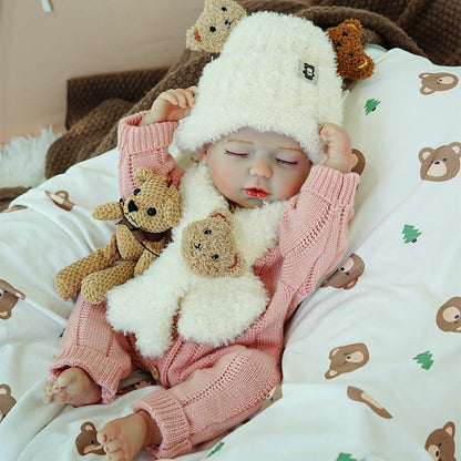 A reborn baby doll wearing a pink sweater and a white sheep hat, holding two stuffed toy bears.