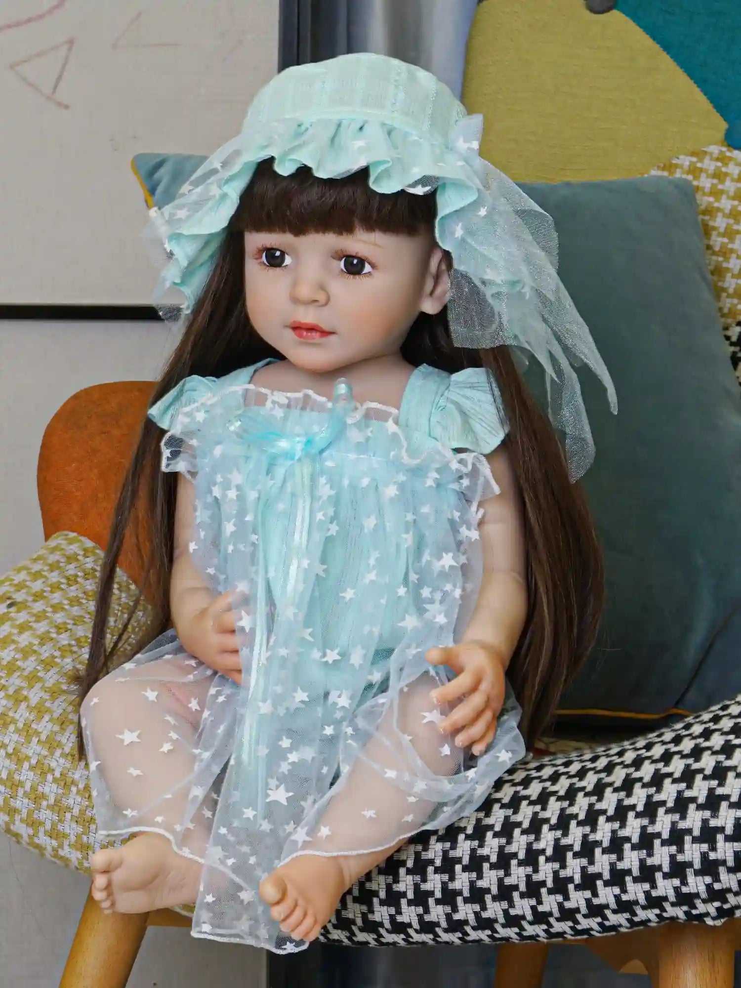 Serene doll in an aqua ensemble with a lacy hat, surrounded by colorful cushions.