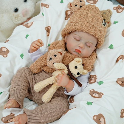 Reborn baby doll sleeping peacefully with a teddy bear, dressed in a cozy outfit.