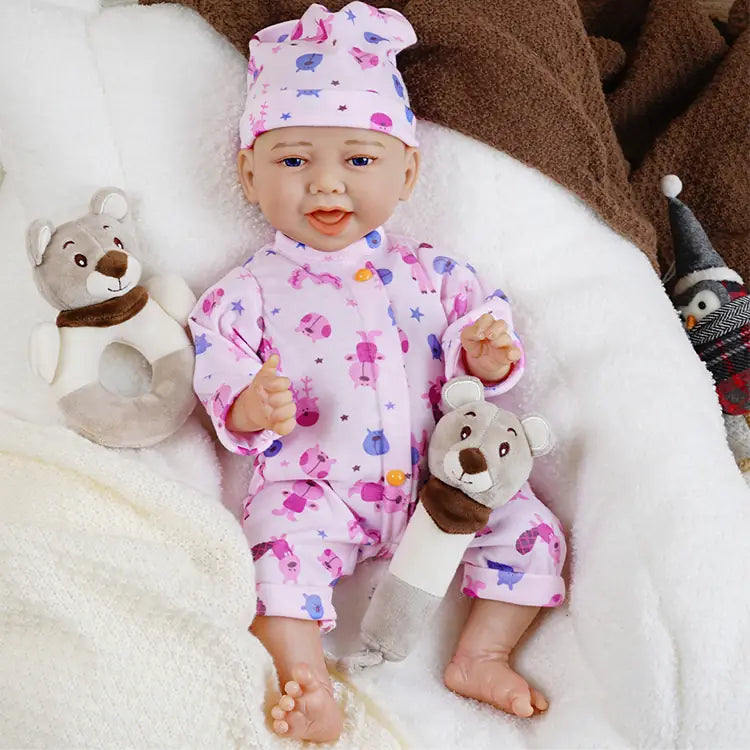 Close-up of a reborn baby doll in a pink chef's hat and pajamas, with a pacifier in its mouth, lying on a white blanket
