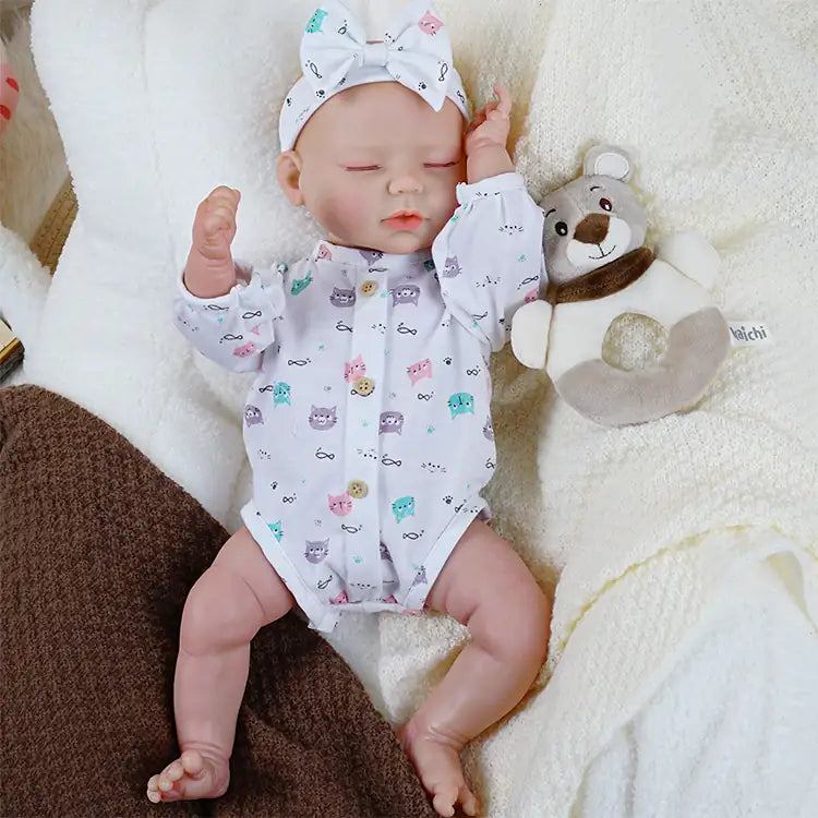 Reborn infant doll with bottle in cat print pajamas.