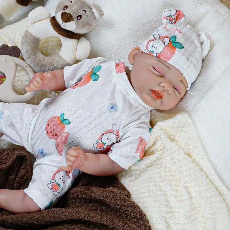 Realistic silicone baby doll in a white fruit-themed outfit, complete with a headband, peacefully sleeping on a fluffy white blanket.