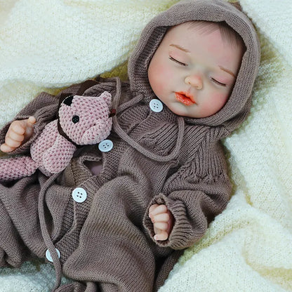  A reborn baby doll dressed in a onesie, holding a pink teddy bear.