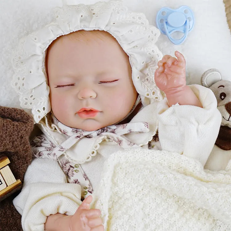 Sleeping reborn baby doll with floral jumpsuit and lace bonnet.