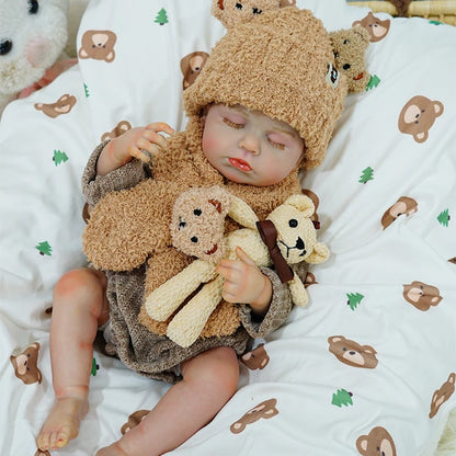 Reborn baby doll sleeping peacefully, cuddling a teddy bear on a bear-themed blanket.