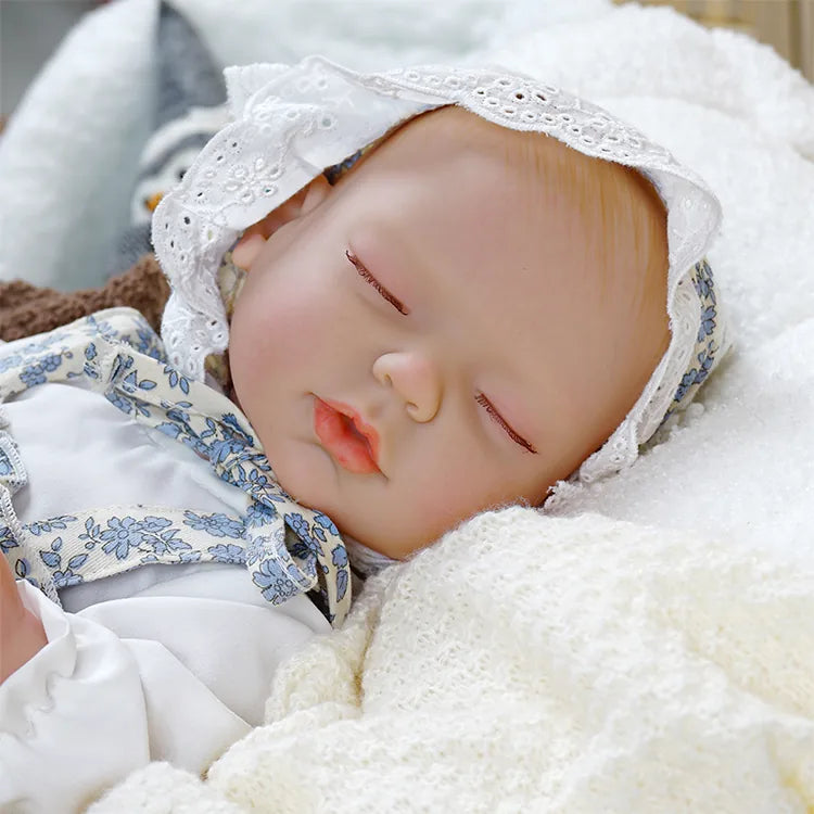Lifelike baby doll with blue floral dress and lace bonnet.