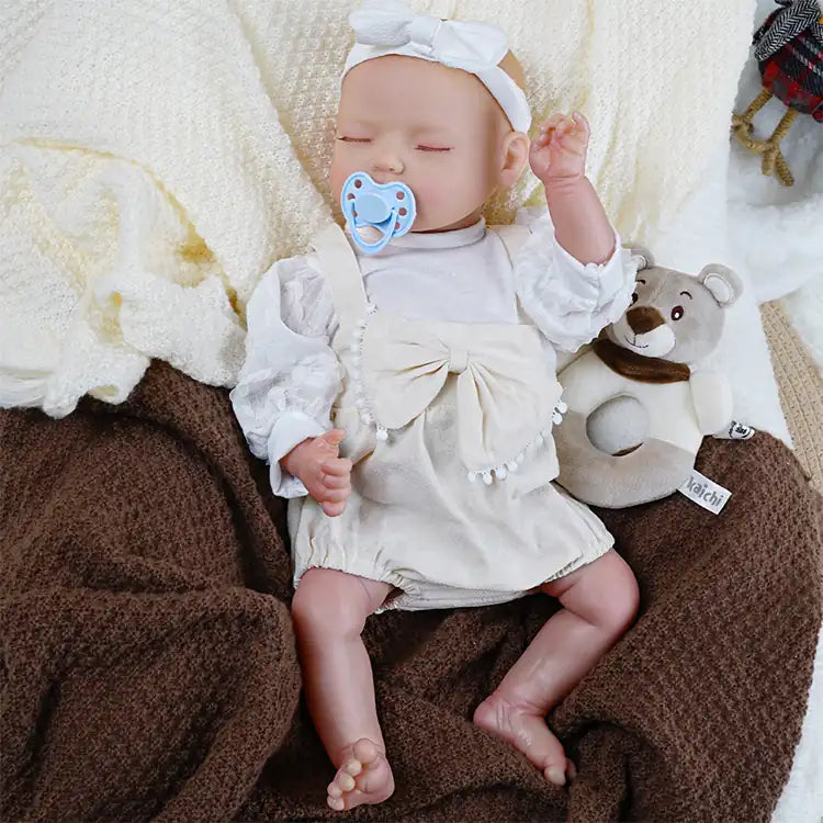 Lifelike baby doll in elegant cream outfit with pacifier.